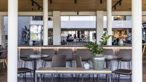 Un café moderne avec un plafond en bois, un bar et différents espaces pour s’asseoir.