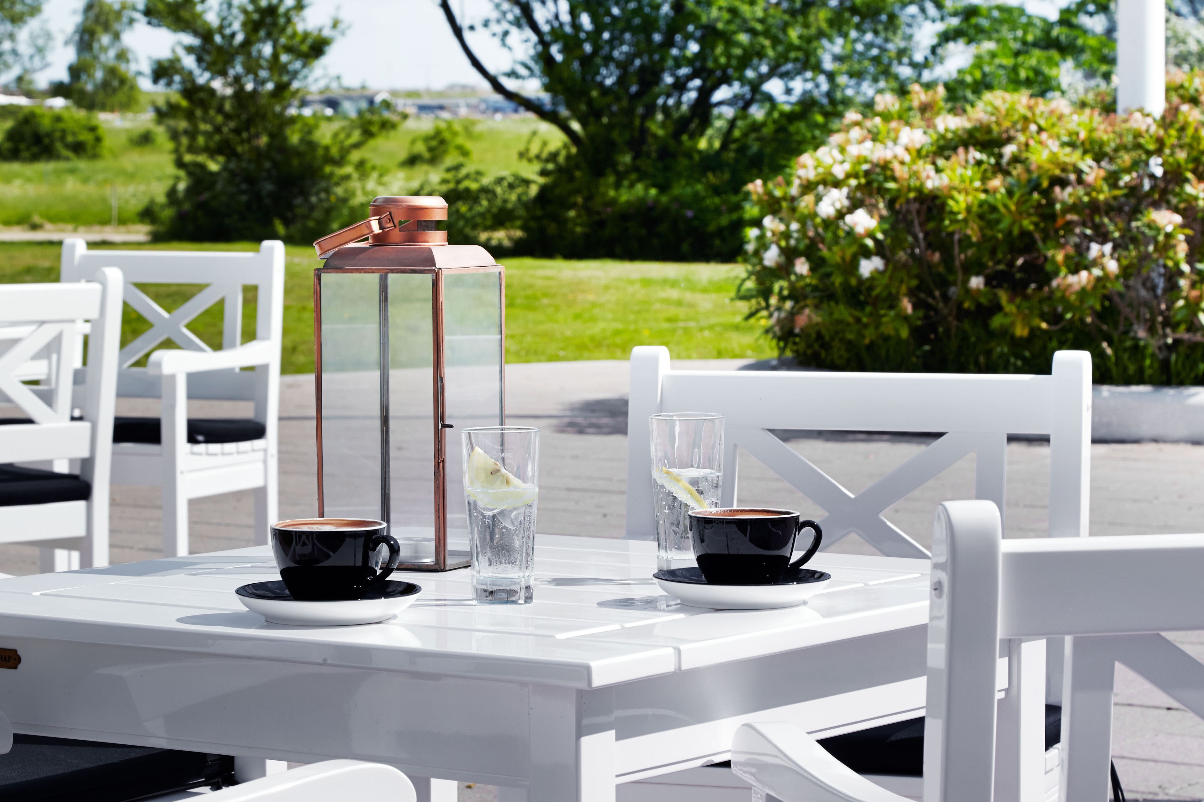 A table with two cups of coffee, a glass of water, and a thermos.