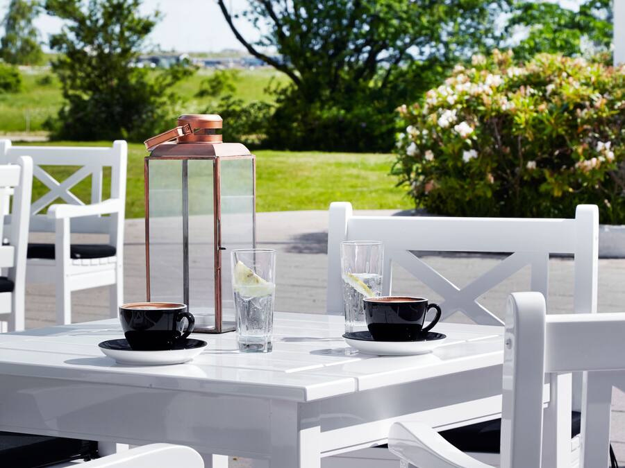 A table with two cups of coffee, a glass of water, and a thermos.