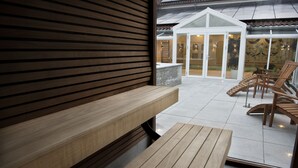 A wooden bench and table on a patio with a view of a building and chairs. - Golf Hotel Viborg (Viborg)