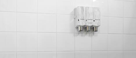 A bathroom with white tiles, a hand dryer, and a towel rack.