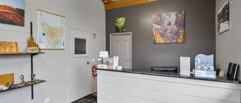 A reception area with a white reception desk, a fire extinguisher, and artwork on the walls.