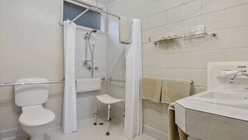A bathroom with a toilet, shower, and sink.