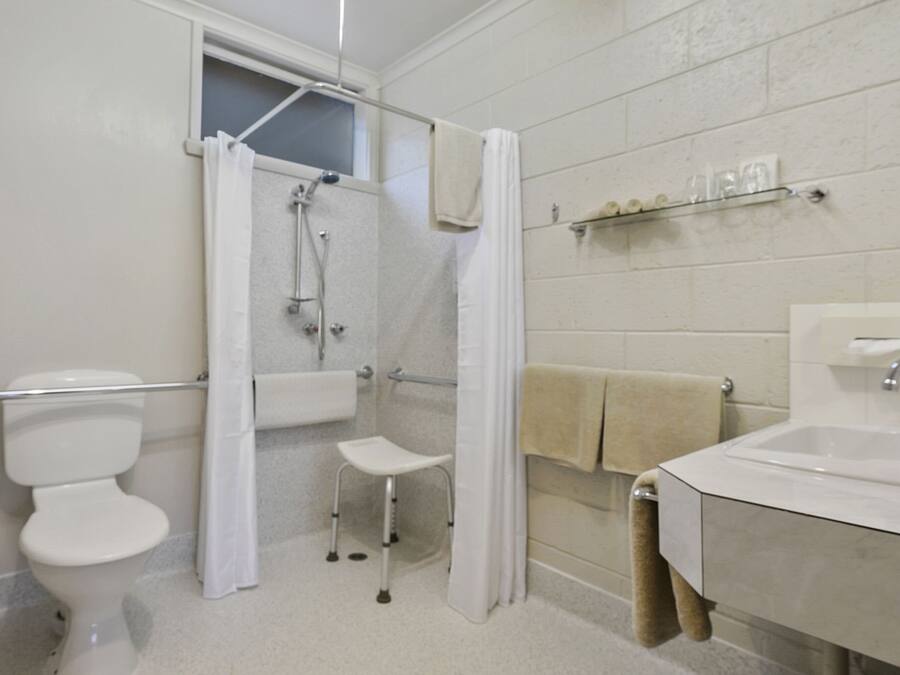 A bathroom with a toilet, shower, and sink.