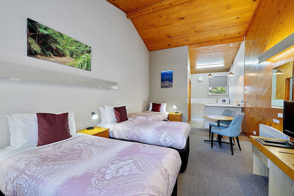 A hotel room with two beds, a desk, and a computer.