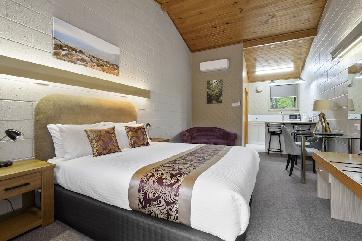 A modern hotel room with a large bed, a desk, and a chair.