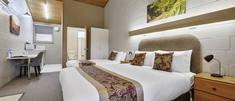 Habitación de hotel con una cama grande, un escritorio, una silla y una mesita.