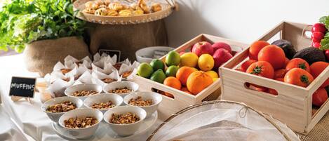 A breakfast buffet with various food items including fruits, muffins, and granola.