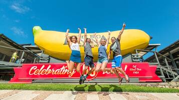 A group of people jumping in front of a large banana-shaped structure with a red banner that reads "Celebrating 22nd Dec 1964".