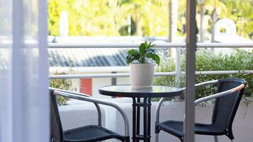 A balcony with a round table, two wicker chairs, and a potted plant.