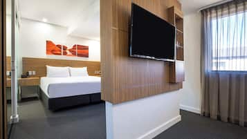 Camera d'albergo con un letto, una TV a schermo piatto montata a parete, un comodino e una finestra con tende.