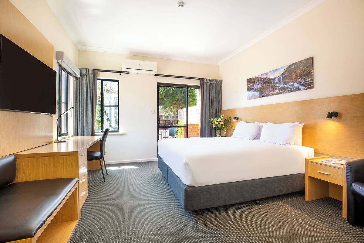Una habitación de hotel con cama, escritorio, silla y televisión.