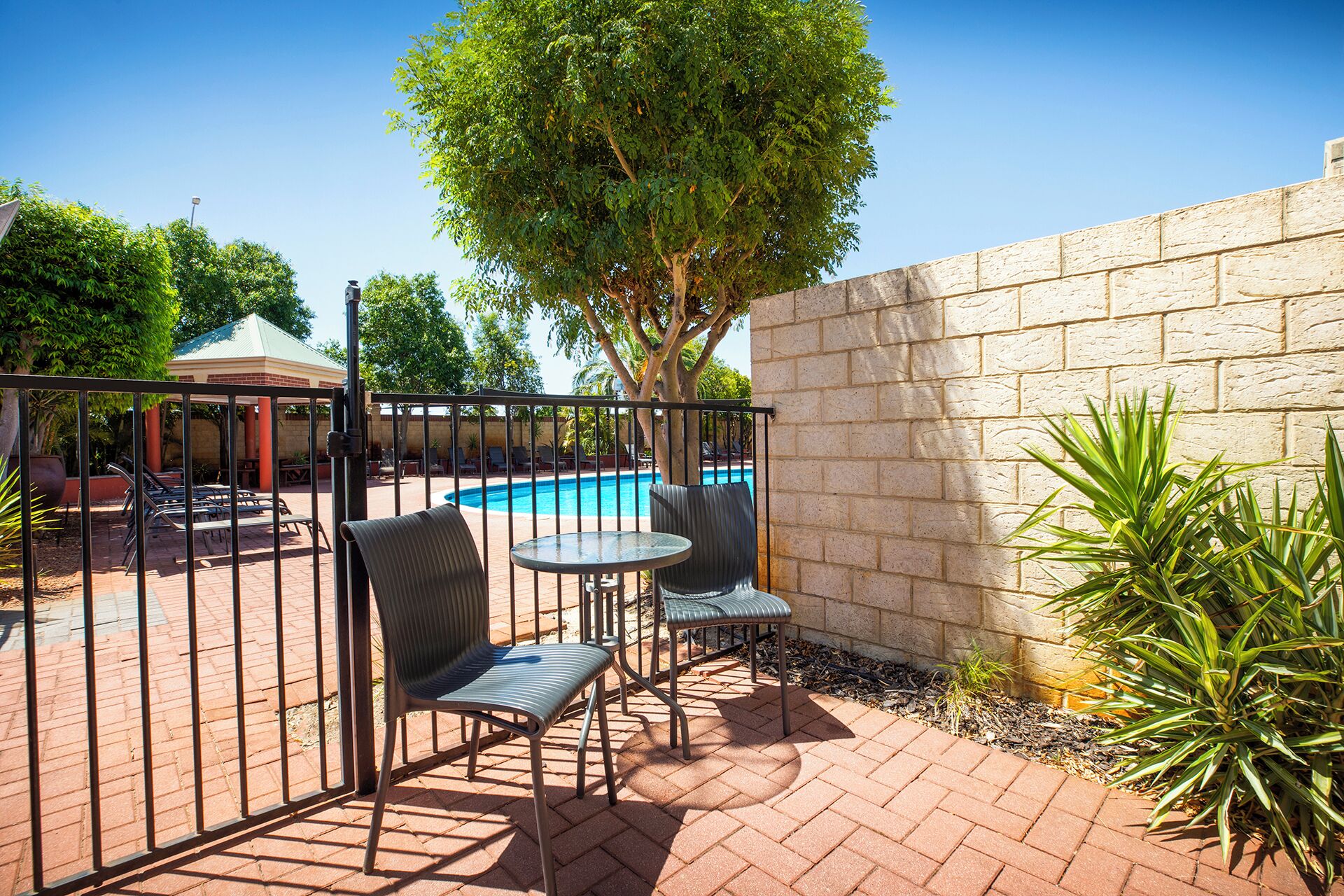 A patio area with a pool, two chairs, and a table.