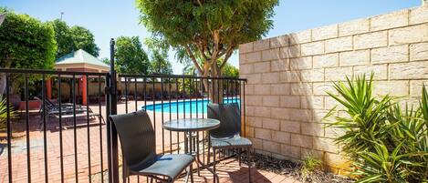 A patio area with a pool, two chairs, and a table.