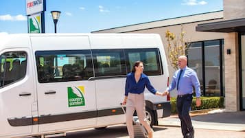Una camioneta blanca con la marca 'country comfort' estacionada frente a un edificio.