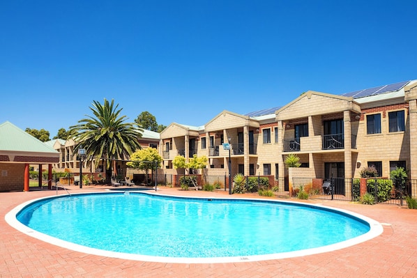 Edificio residencial con piscina, fachada de ladrillo y varios balcones.