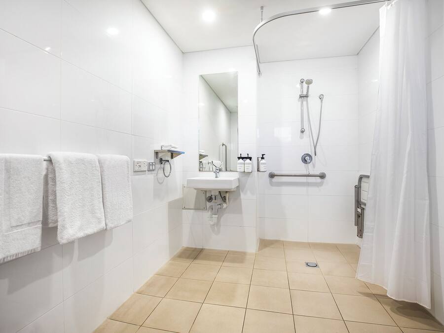 A modern bathroom with white tiles, a sink, a mirror, and a shower with a curved door.
