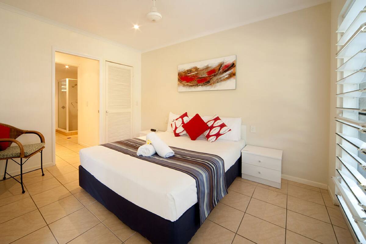 Une chambre à coucher comprenant un lit, une chaise, une table de chevet, une commode, un tableau et un placard.