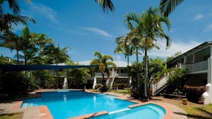A swimming pool surrounded by palm trees and a building with a staircase leading to a balcony. - Mango House Resort (Jubilee Pocket)