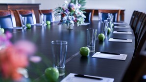 A conference table with chairs, a vase of flowers, and documents. - Rydges Armidale (Armidale)