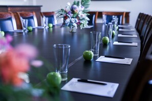 A conference table with chairs, a vase of flowers, and documents. - Rydges Armidale (Armidale)