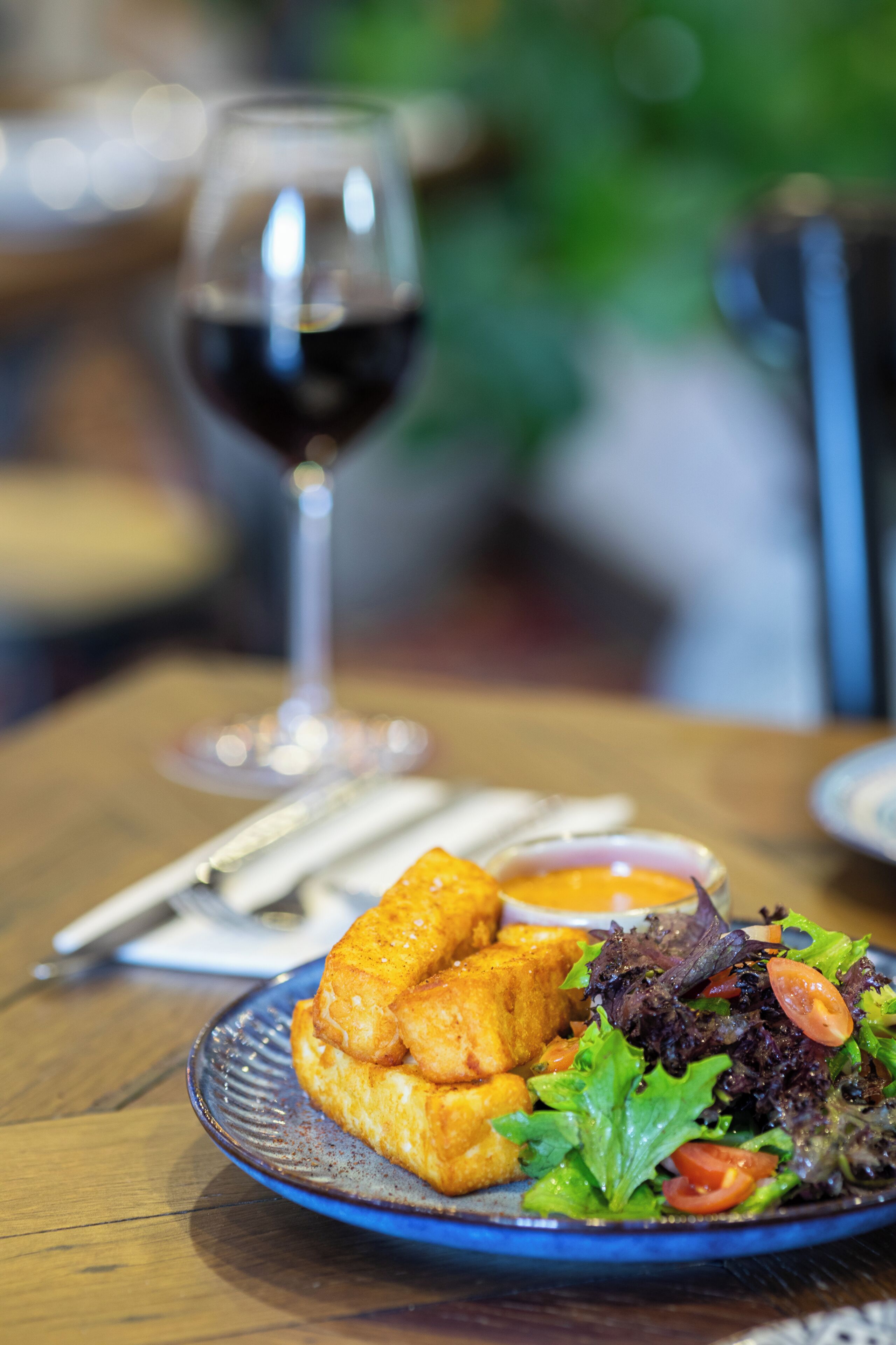 A plate of food with a glass of red wine on a wooden table.