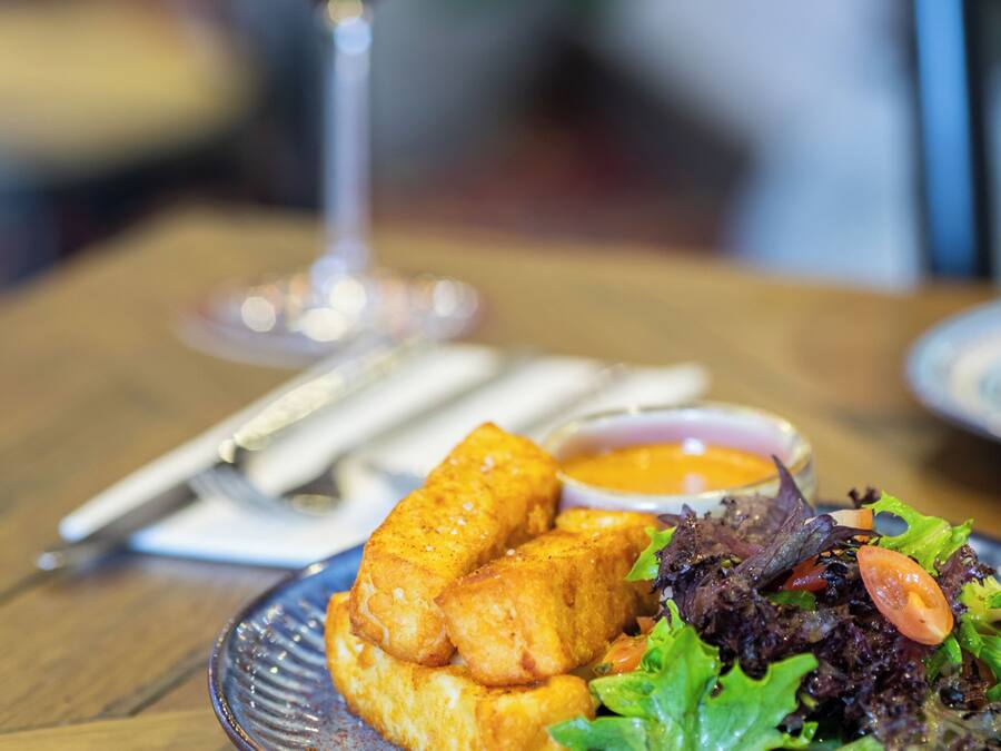 Une assiette de nourriture accompagnée d’un verre de vin rouge, le tout posé sur une table en bois.