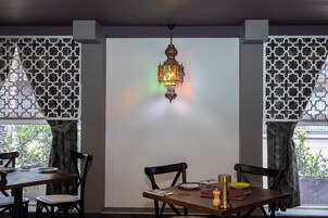 Un comedor con una mesa dispuesta para dos, una lámpara decorativa colgante y cortinas con diseño.