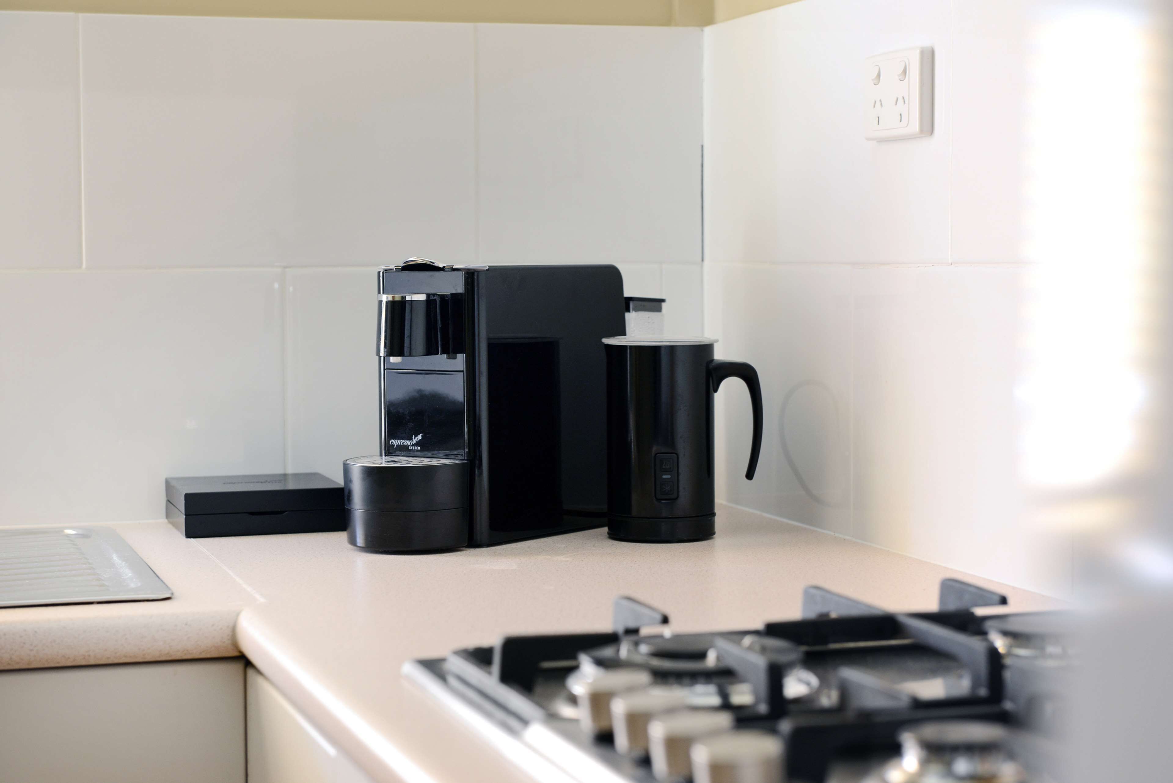 Una cocina moderna con cafetera, hervidor y tostadora sobre la encimera.