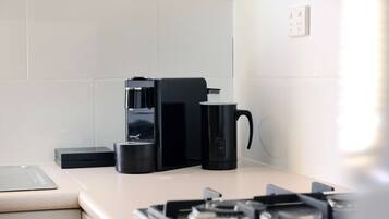Una cocina moderna con cafetera, hervidor y tostadora sobre la encimera.