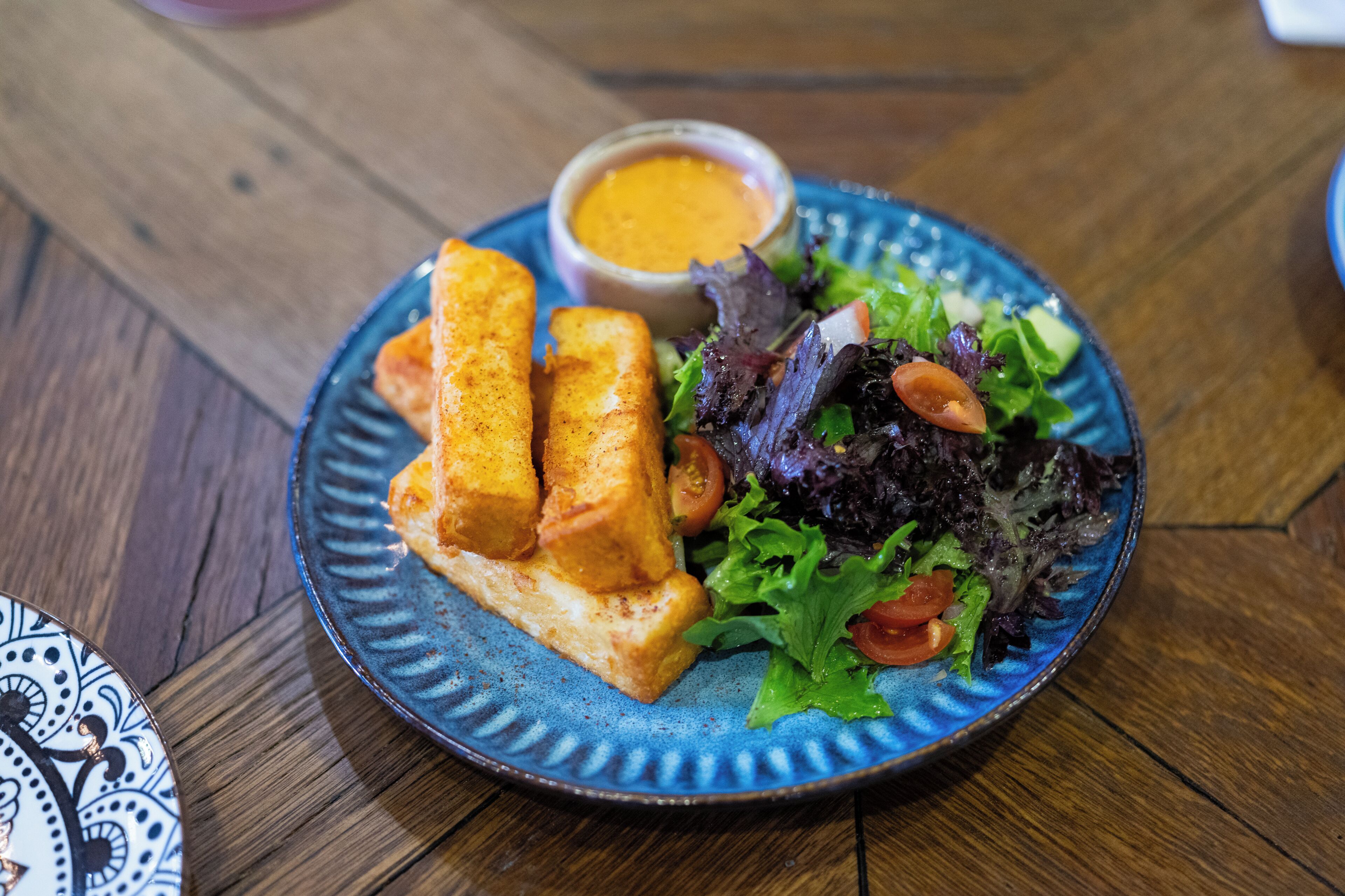 A plate with food items including a salad and a dipping sauce.