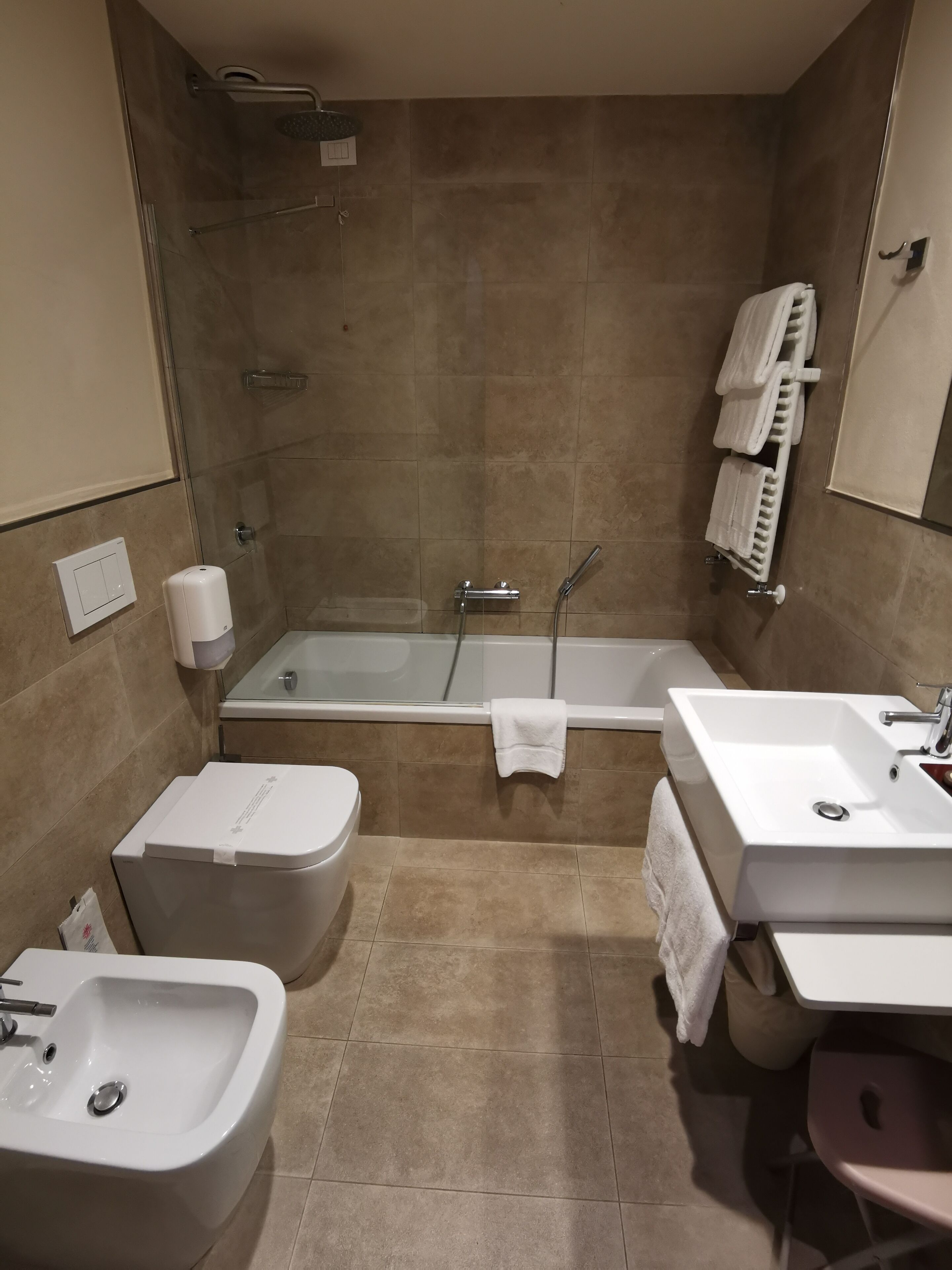 Ein Badezimmer mit Badewanne, einer Bidet-Funktion, Waschbecken und Spiegel.