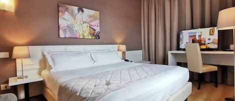 Una habitación de hotel con una cama grande, dos mesitas de noche con lámparas, un escritorio con silla, un televisor y un cuadro en la pared.