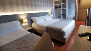 Una habitación de hotel con dos camas, un armario, un escritorio con lámpara y un televisor.