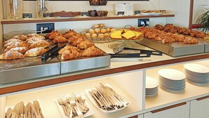 Un mostrador buffet con diversos pasteles, croissants y una exhibición de utensilios.