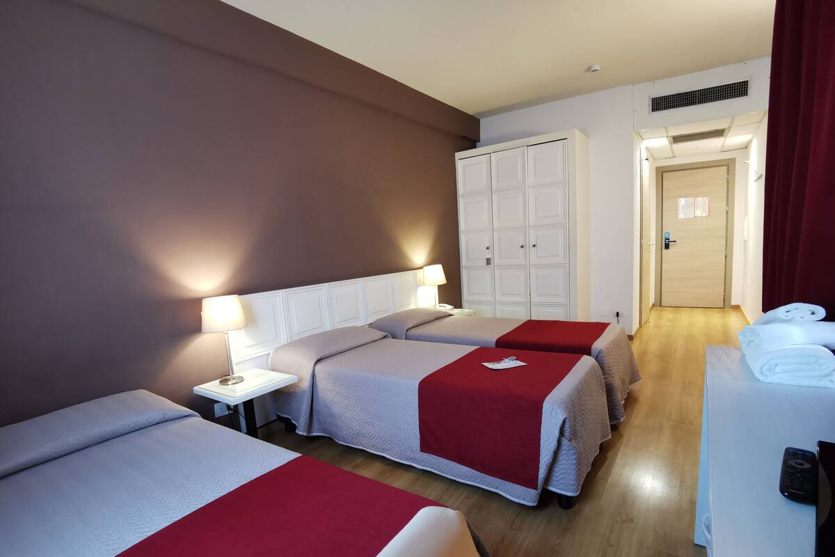Habitación de hotel con dos camas, un escritorio, un armario y una puerta.