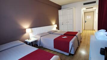 A hotel room with two beds, a desk, a wardrobe, and a door.