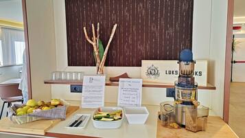 Ein Hotel-Empfangsbereich mit einer Auswahl an Obst und Gemüse, einer Kaffeemaschine und einem Schild, das das Verbot von Obst kennzeichnet.