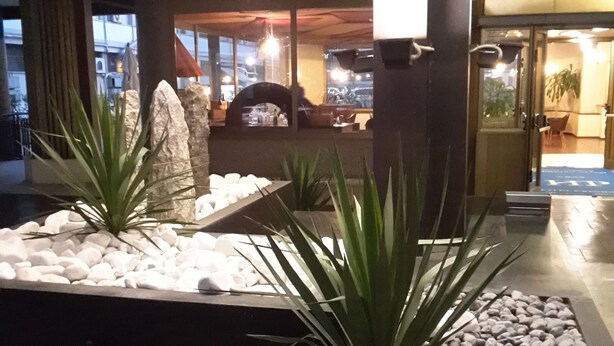 Un jardín interior moderno con zona de estar, chimenea y vistas a la ciudad a través de grandes ventanales.