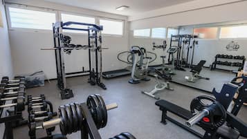 A gym with various exercise equipment, including weight machines, free weights, and cardio machines.