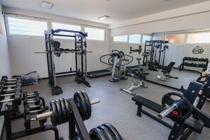 Een sportschool met diverse fitnessapparaten, waaronder krachtapparaten, gewichten en cardioapparatuur.