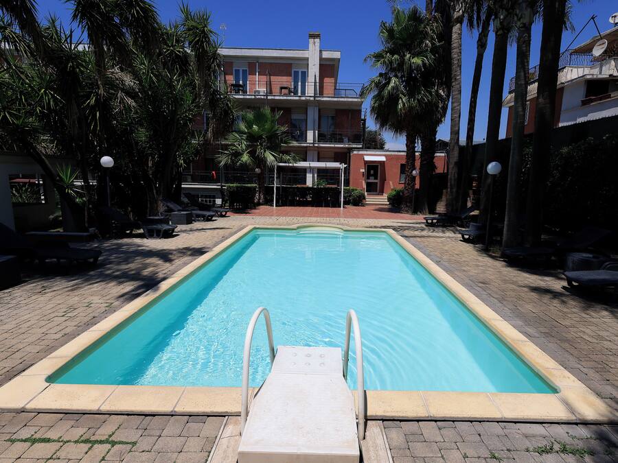 A rectangular swimming pool with a white edge and a metal ladder leading into it.