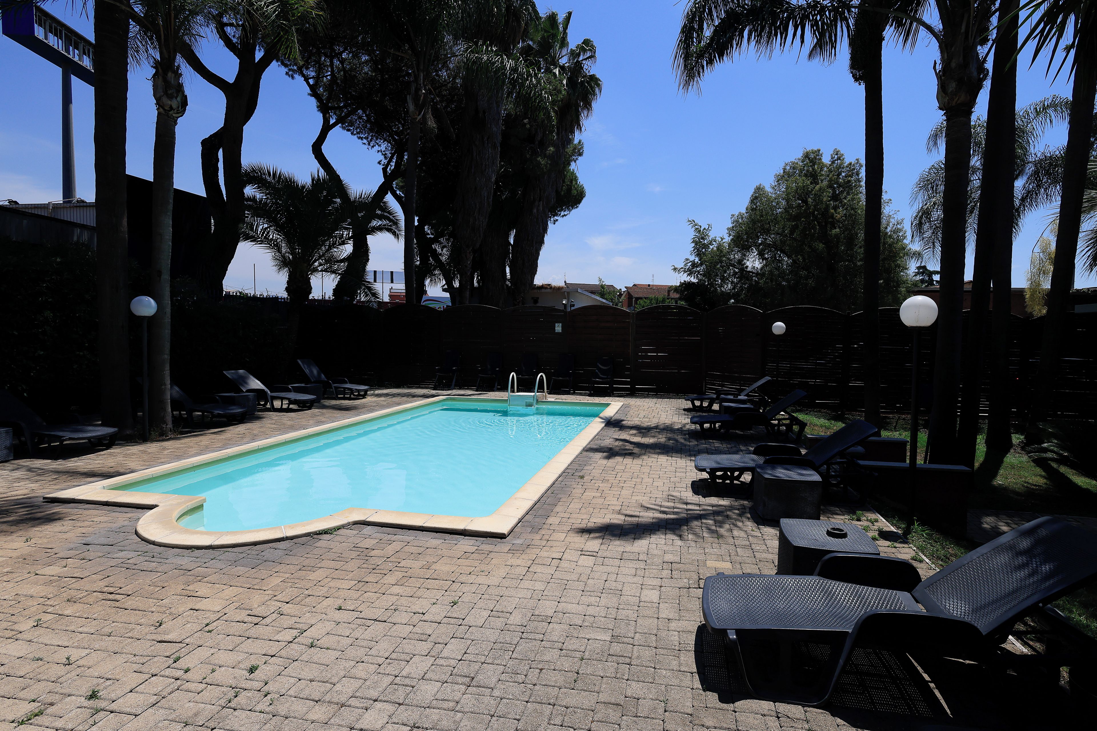 A swimming pool with lounge chairs and palm trees.