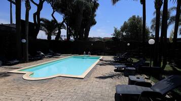 A swimming pool with lounge chairs and palm trees.