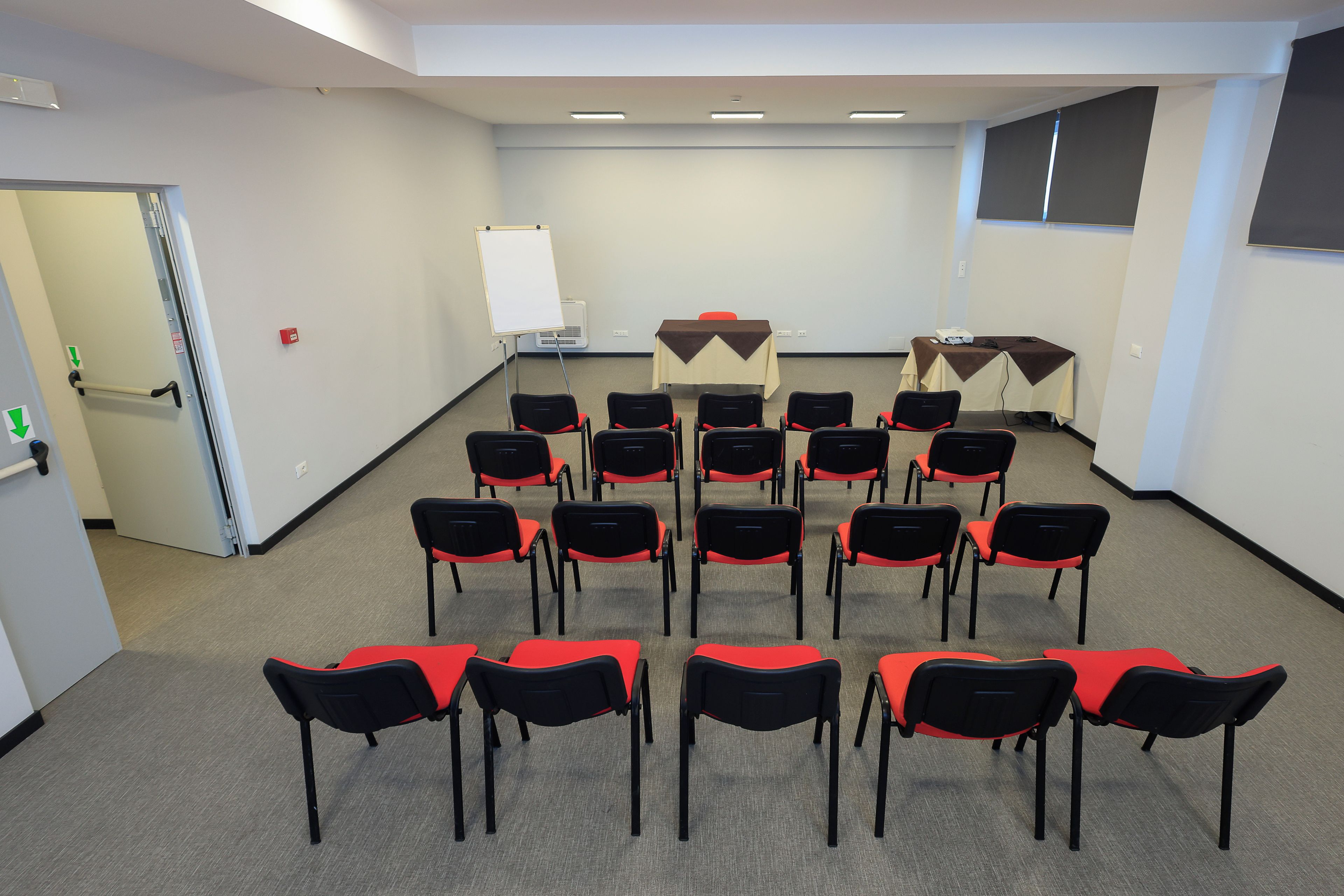 Una sala conferenze con file di sedie, una lavagna e tavoli con proiettori.