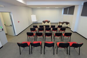 Een vergaderzaal met rijen stoelen, een whiteboard en tafels met projectoren.