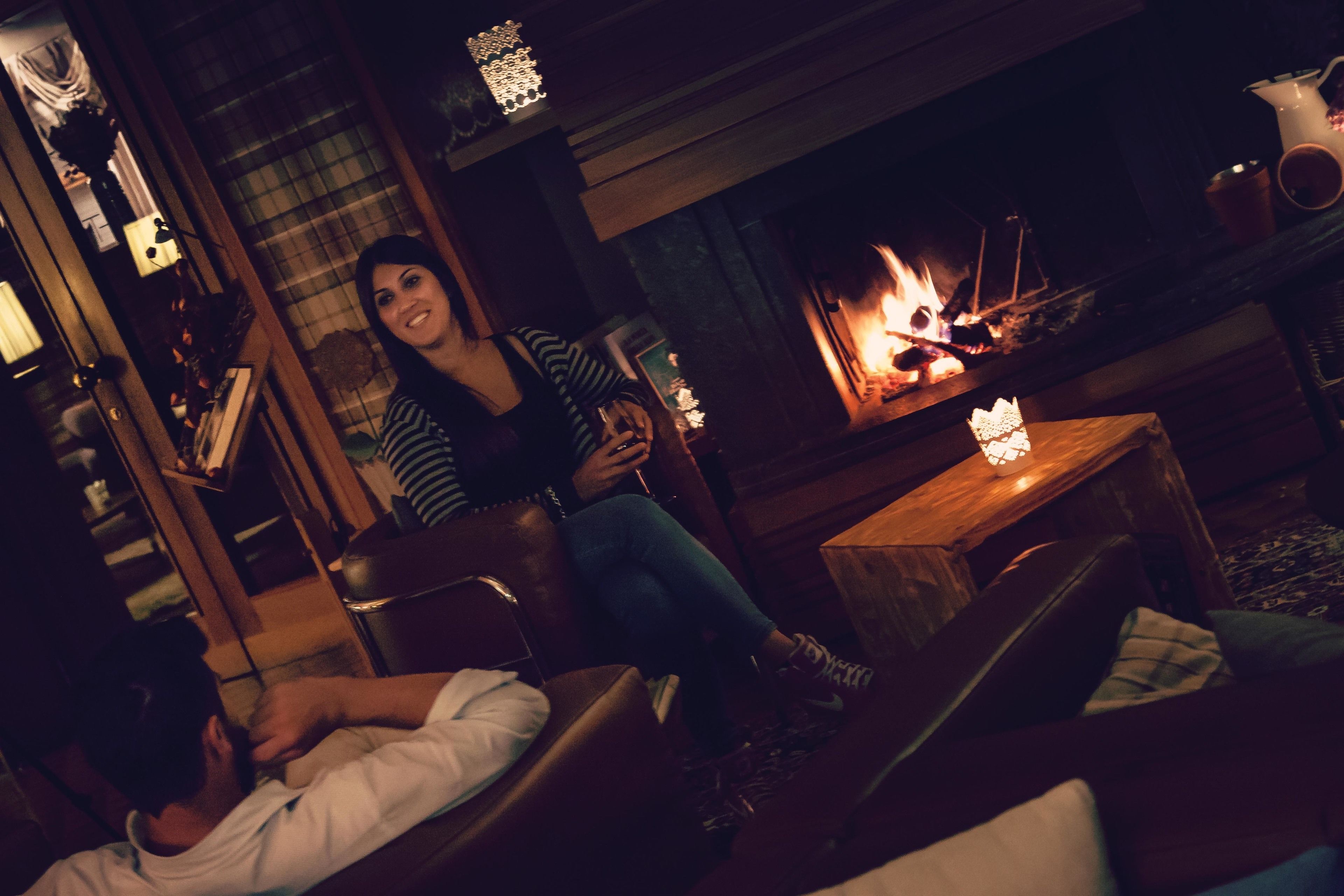 A cozy room with a fireplace, leather seating, and a person lying on a couch.