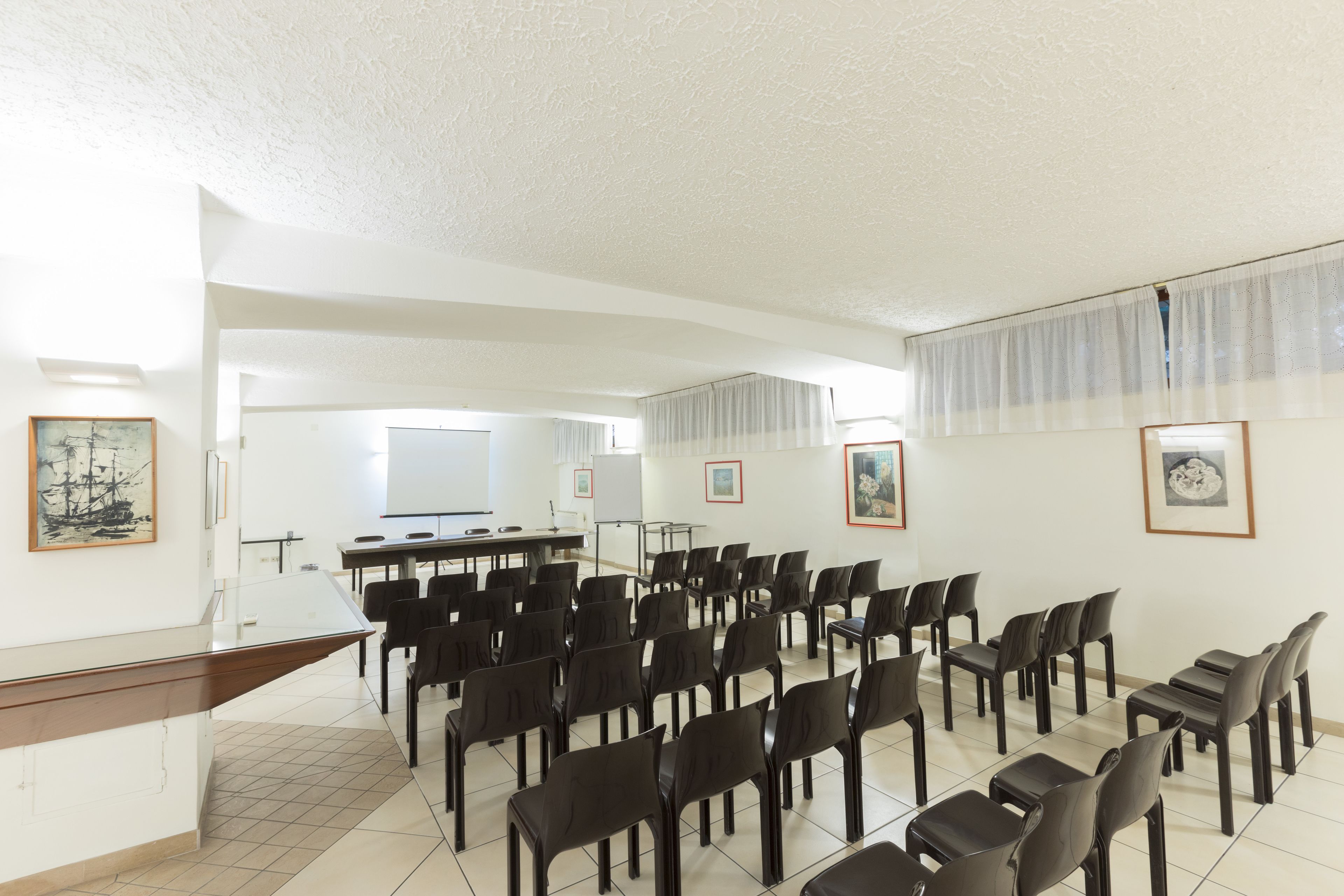 Un salón de conferencias con filas de sillas, un atril y una pizarra.