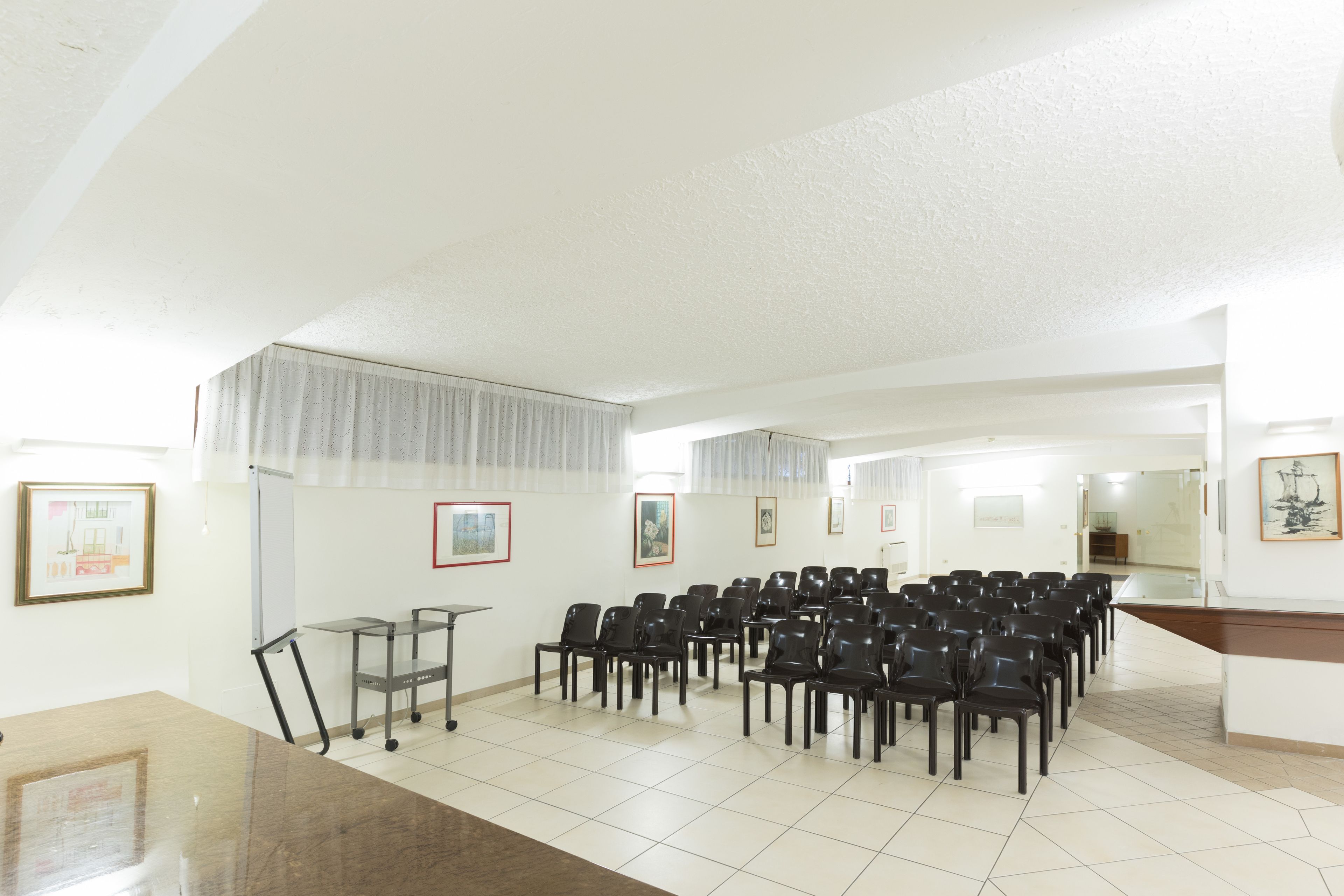 A conference room with rows of chairs, a whiteboard, and framed pictures on the walls.