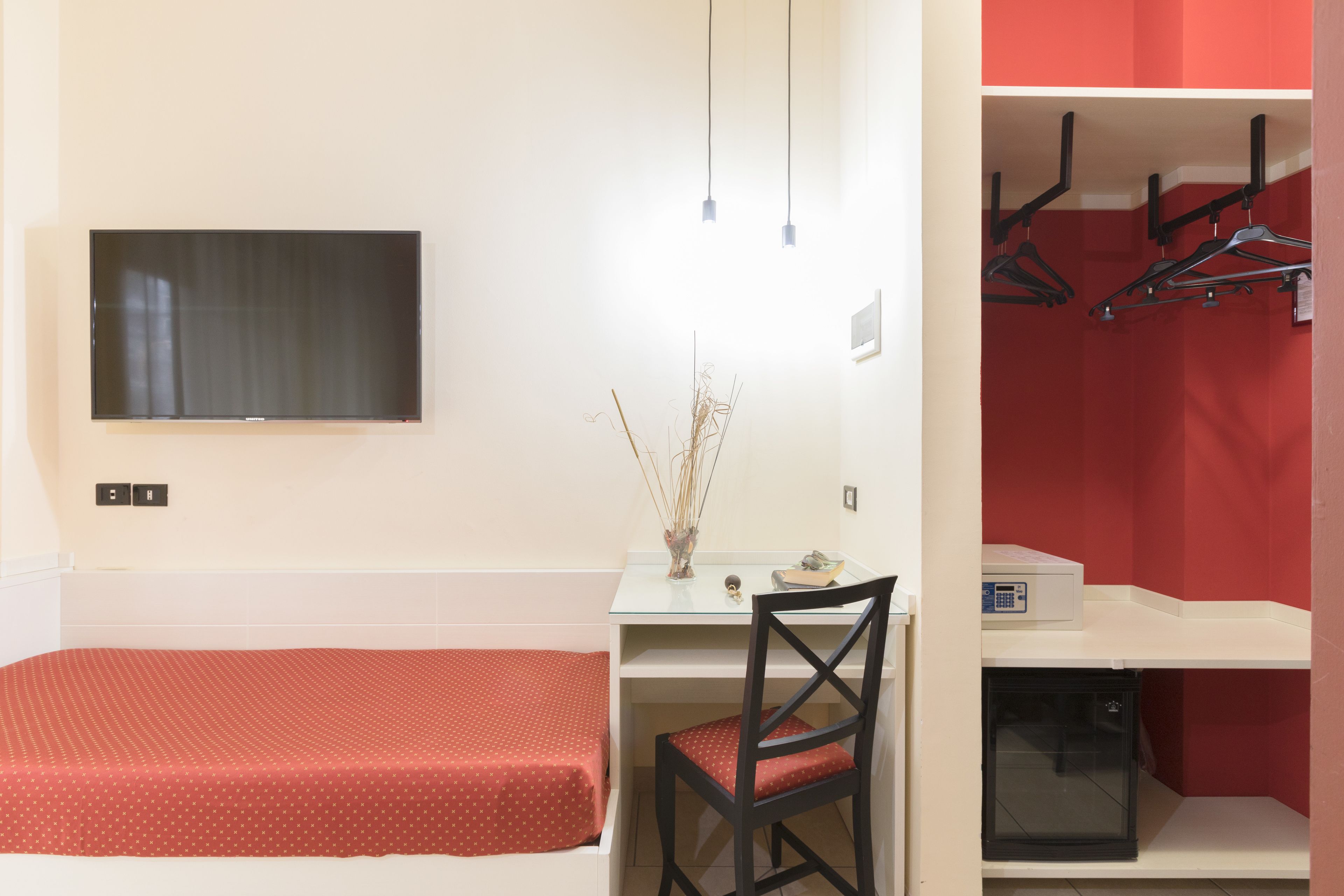 A room with a bed, a desk, a chair, a TV, and a microwave.